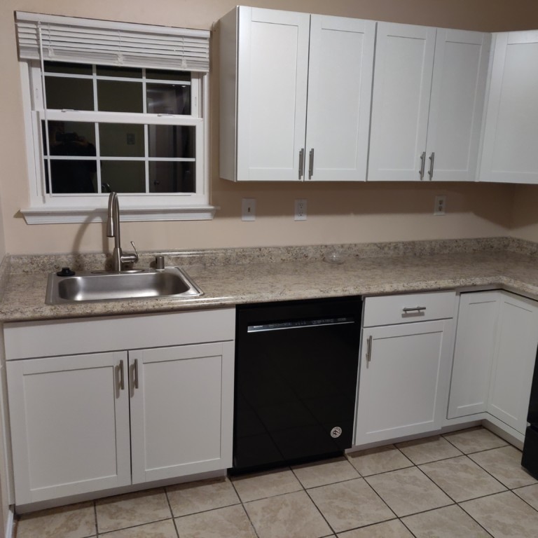 photograph of a single home kitchen with white cabinets & beige tile flooring that was installed by Graham Home Solutions LLC